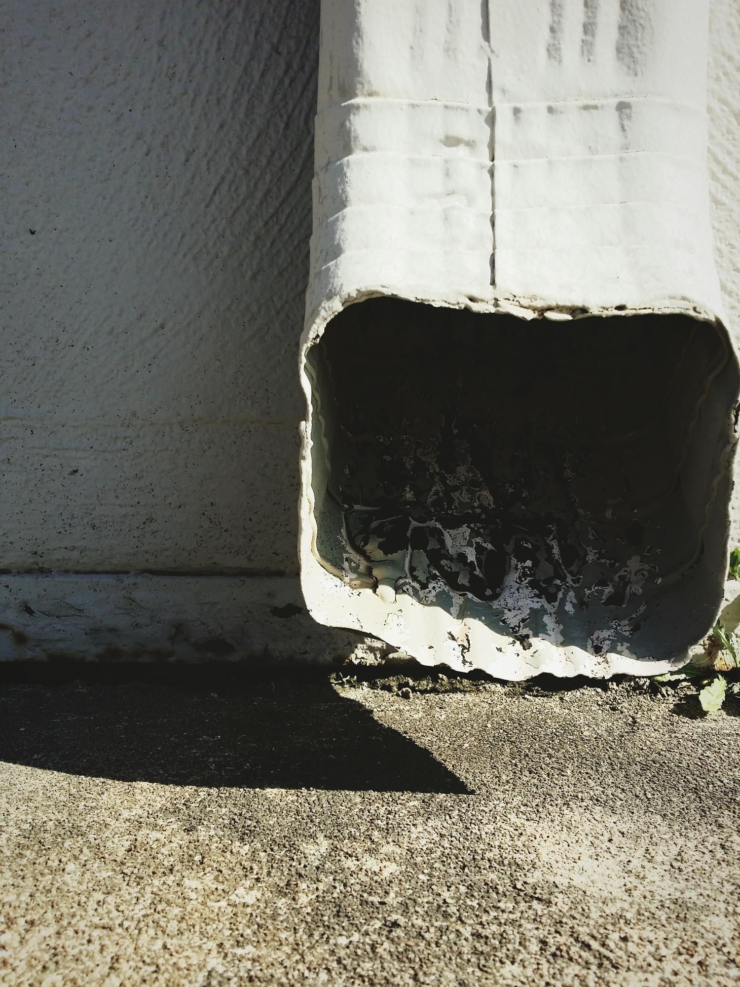 A drainpipe is sitting on the ground next to a wall