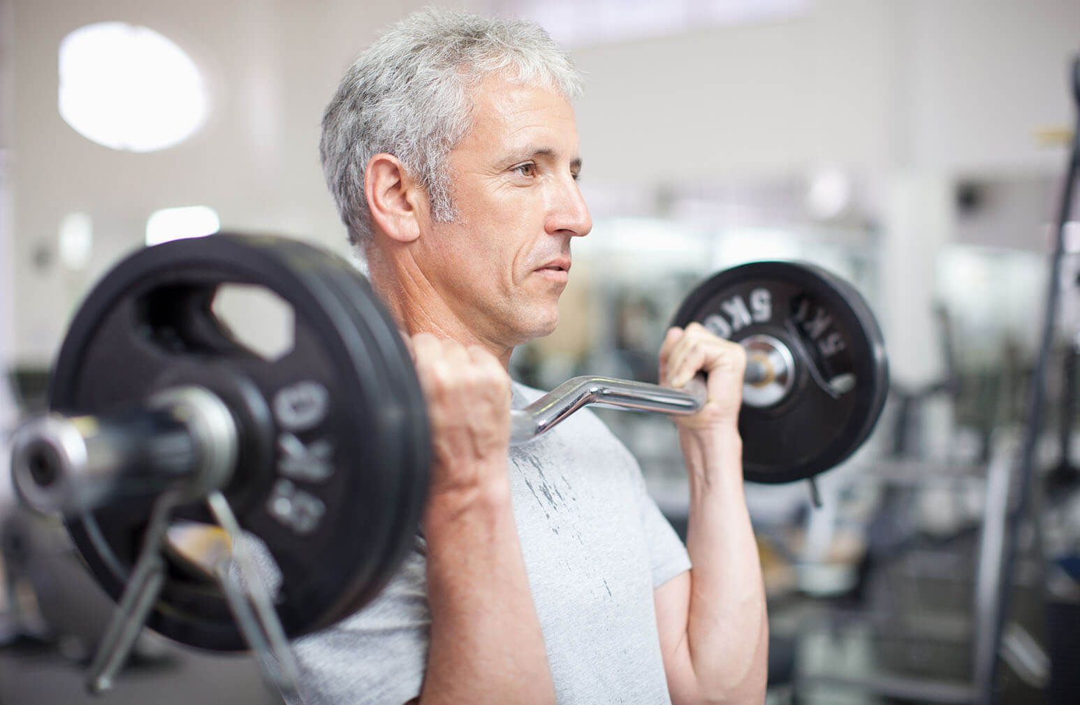 A man is lifting a barbell in a gym.