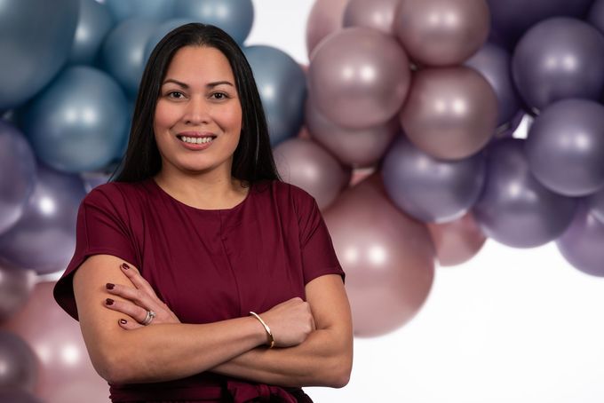 A woman is standing in front of a bunch of balloons.