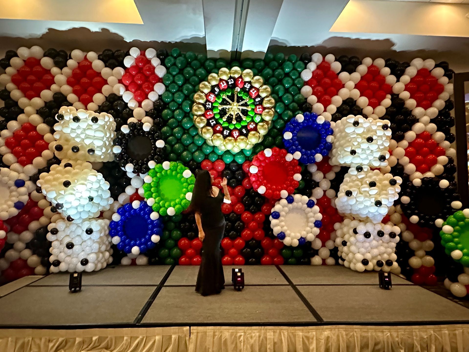 A woman is standing in front of a wall made of balloons