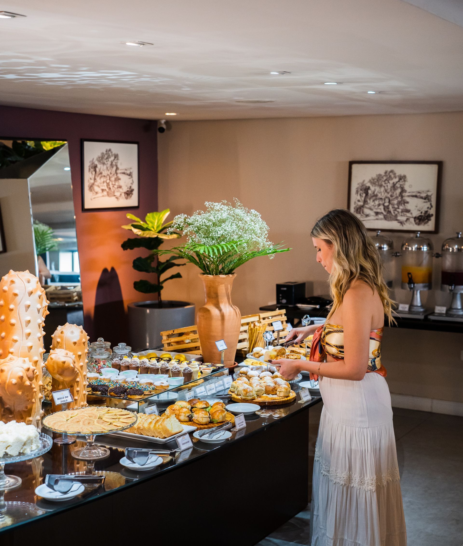 Mulher em um buffet de café da manhã com doces e suco.