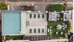 Espreguiçadeiras à beira da piscina com vista para o oceano sob um céu azul com nuvens.