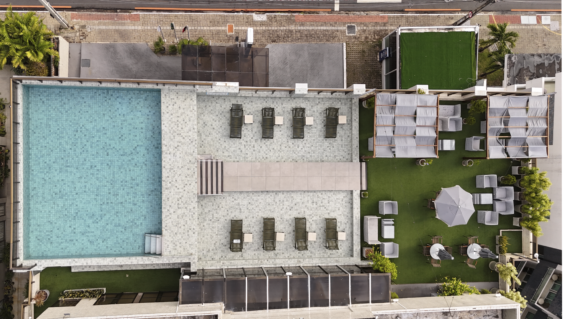 Terraço na cobertura com piscina, vista para o mar e mobiliário de exterior. Céu nublado.