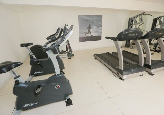 Academia com bicicletas ergométricas, esteiras e aparelhos de musculação.
