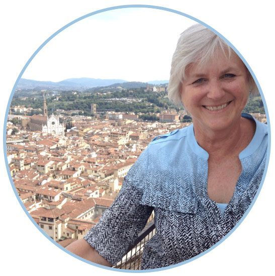 A woman in a blue shirt is smiling in front of a city A woman in a blue shirt is smiling in front of a city