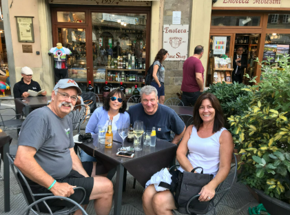 A group of people are sitting at a table in front of a store. A group of people are sitting at a table in front of a store.