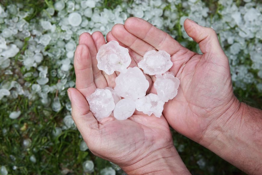 A person is holding a pile of hail in their hands.