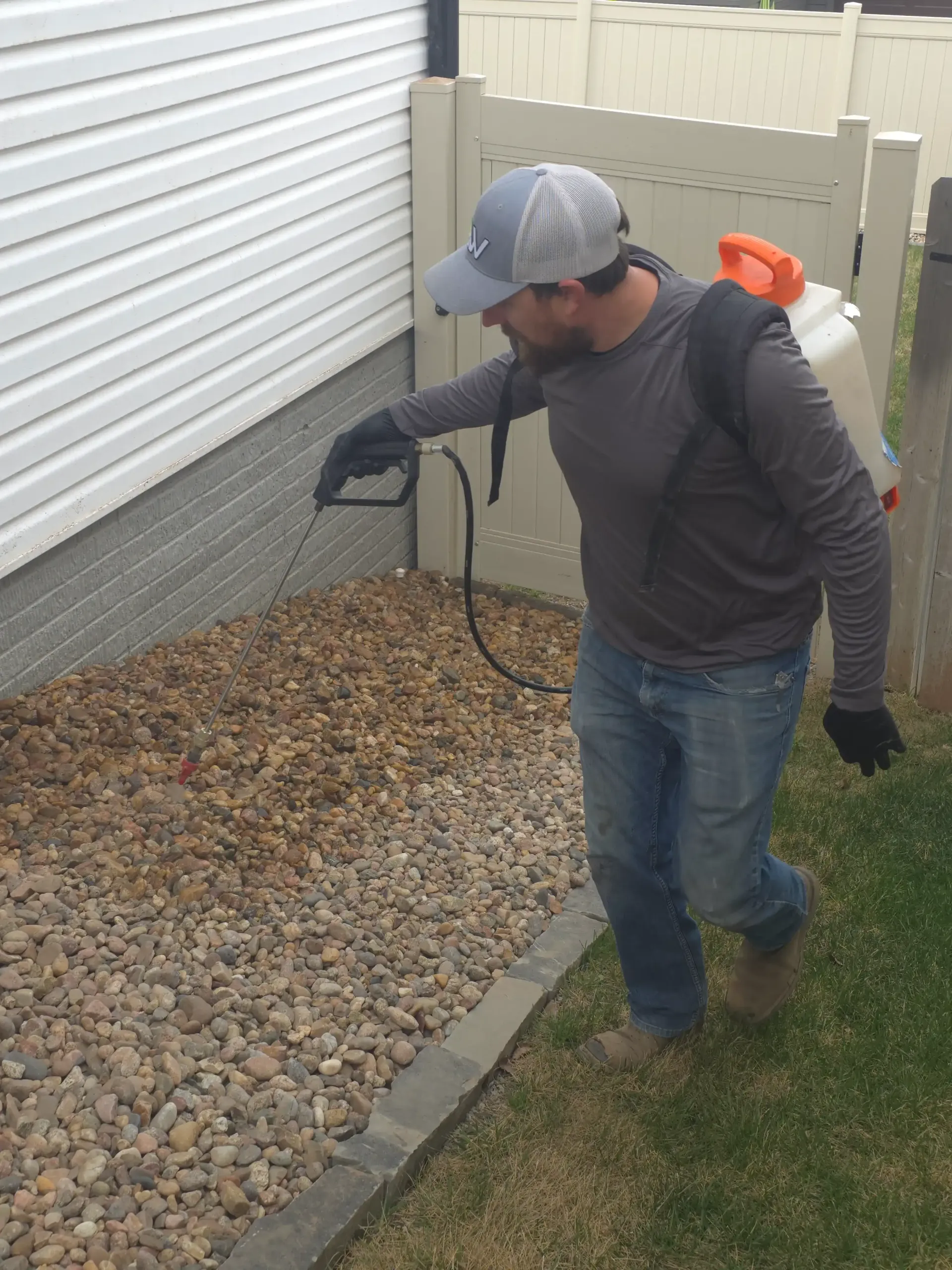 A man spraying a rocky area with a sprayer