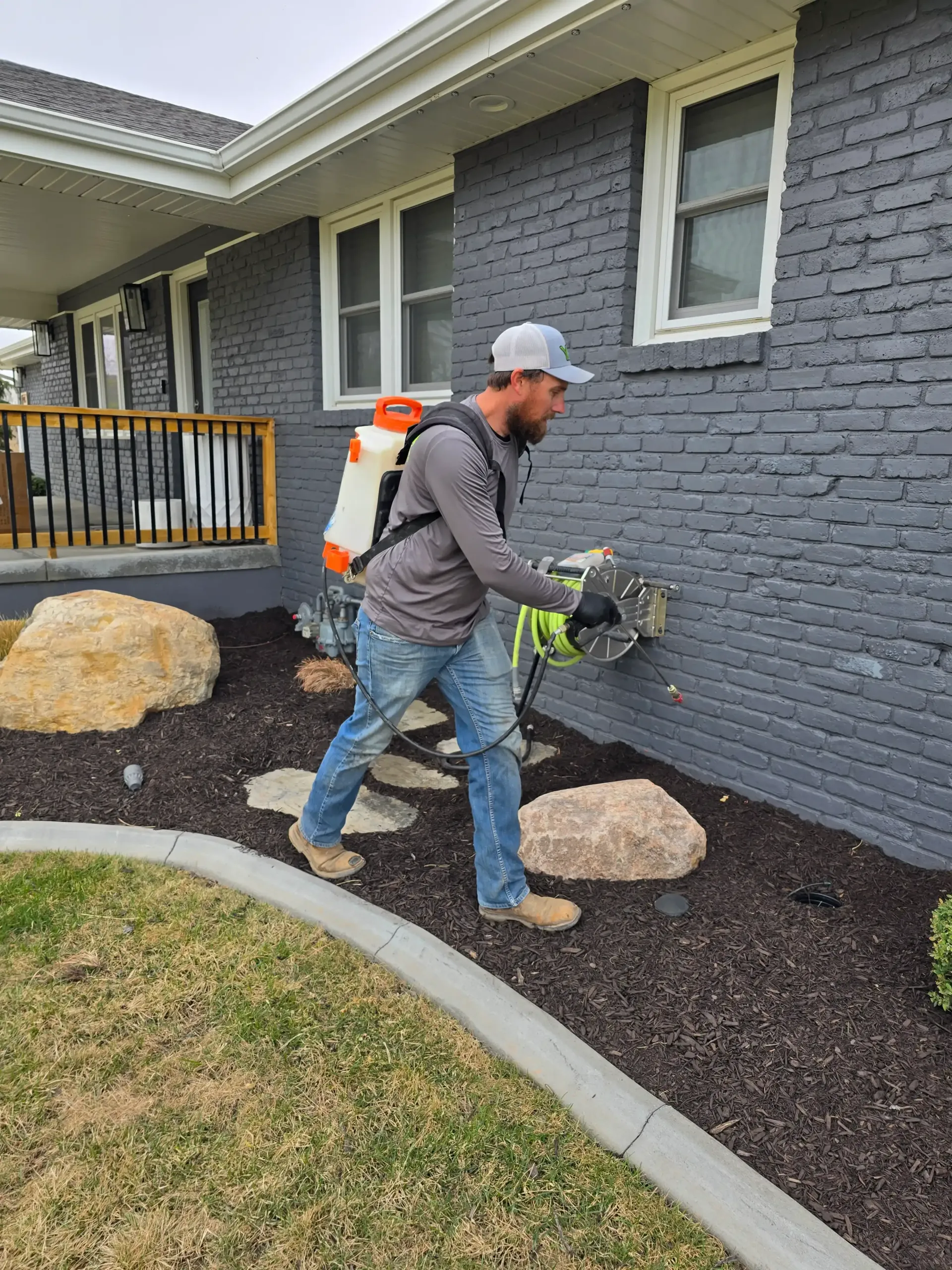 A man is spraying a house with a backpack.