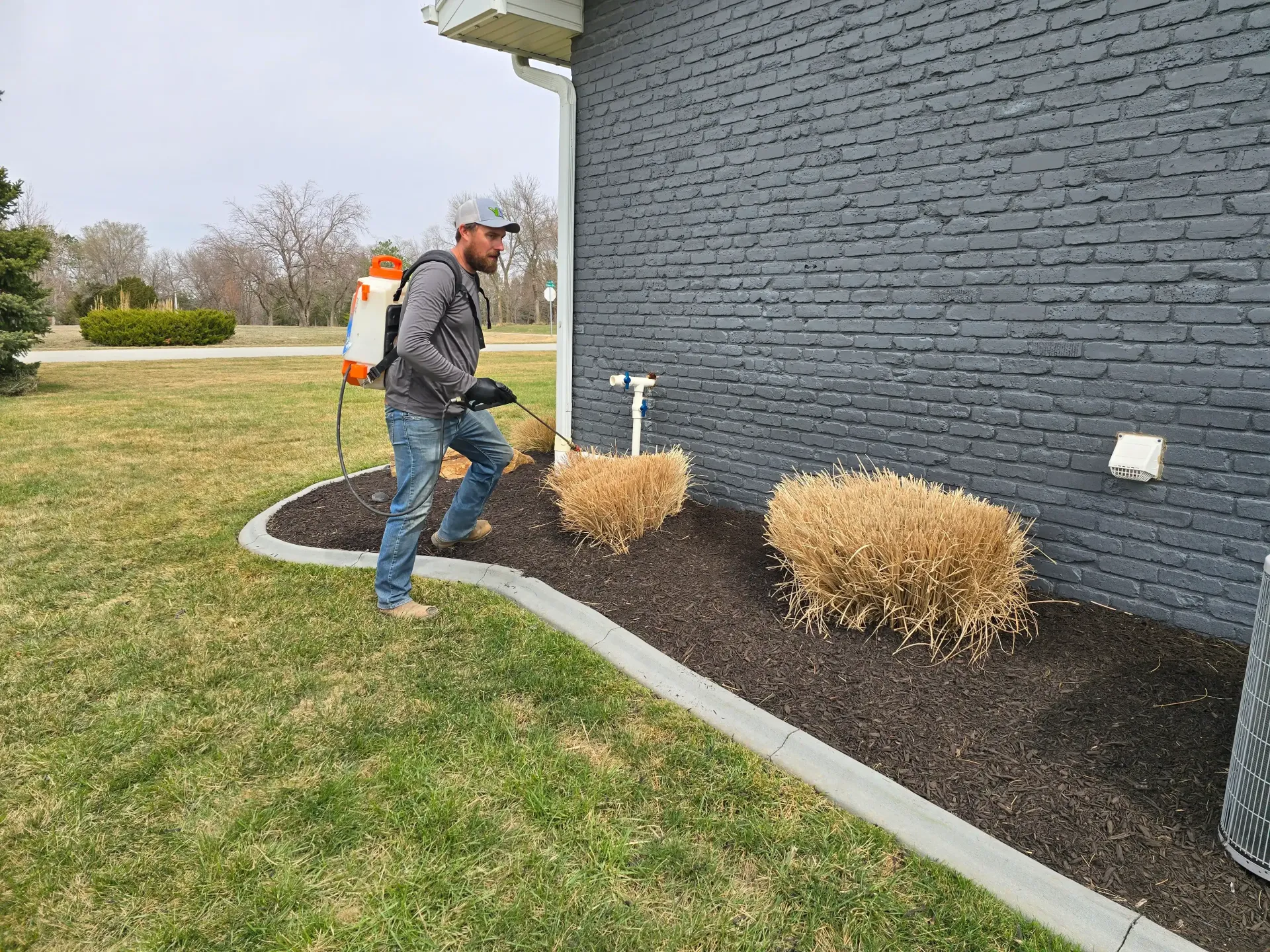 A man is using a lawn mower to mow the lawn in front of a house.