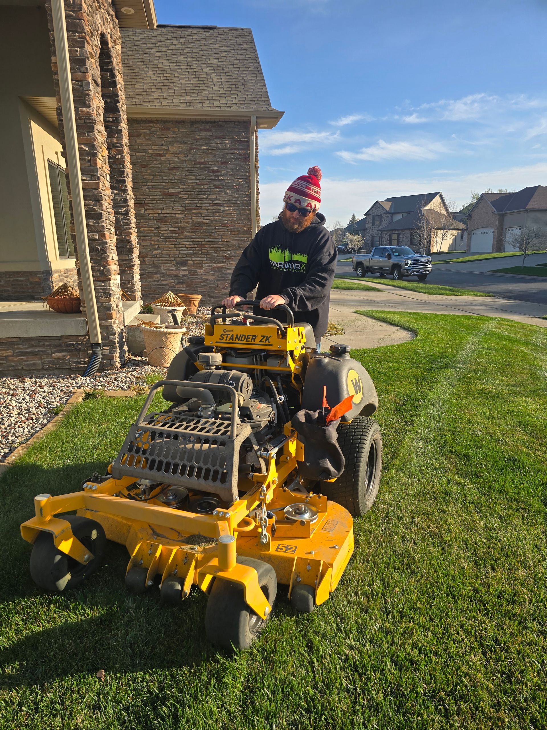 A man is riding a yellow lawn mower on a lush green lawn.