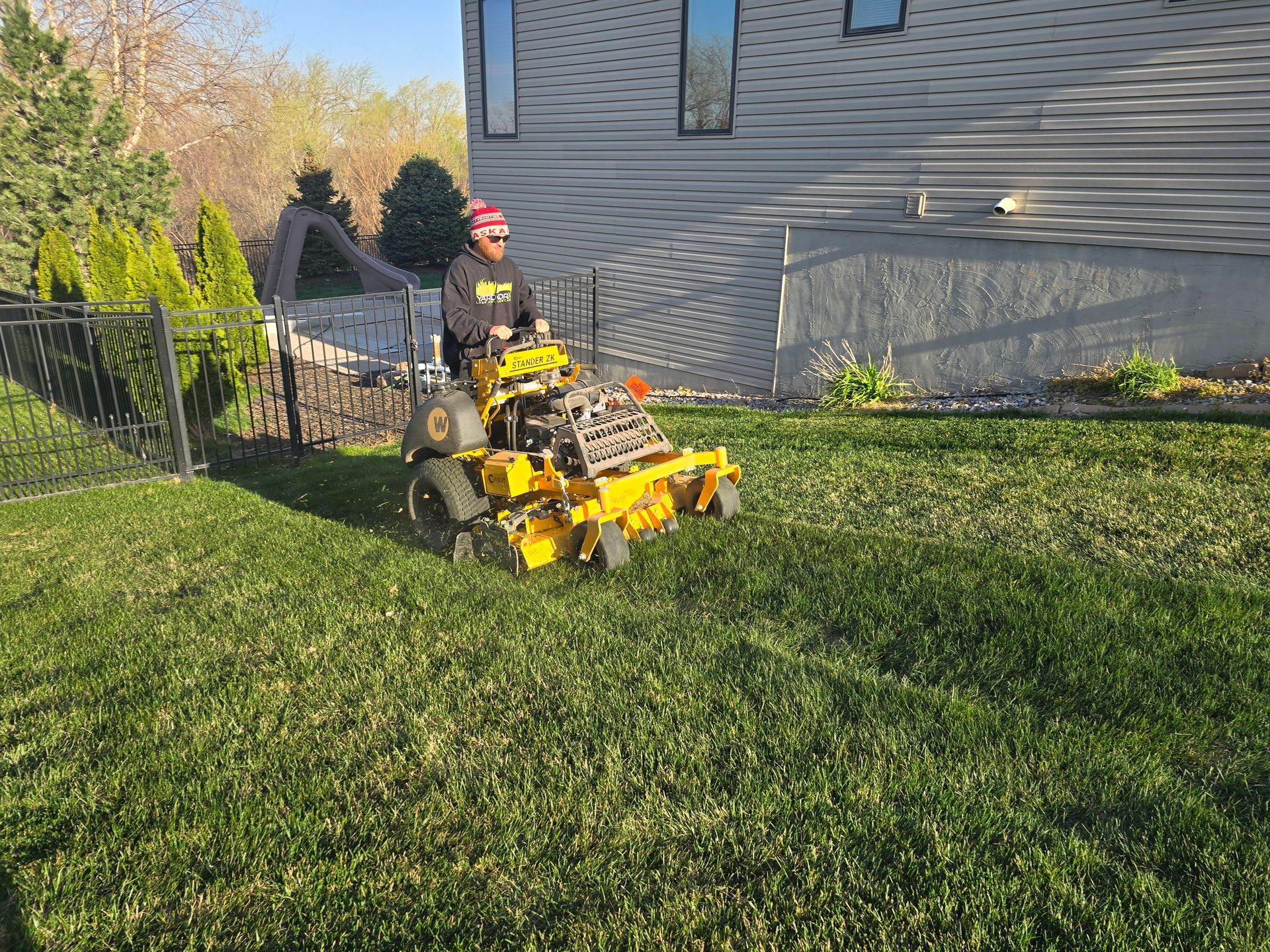 A man is riding a yellow lawn mower on a lush green lawn.