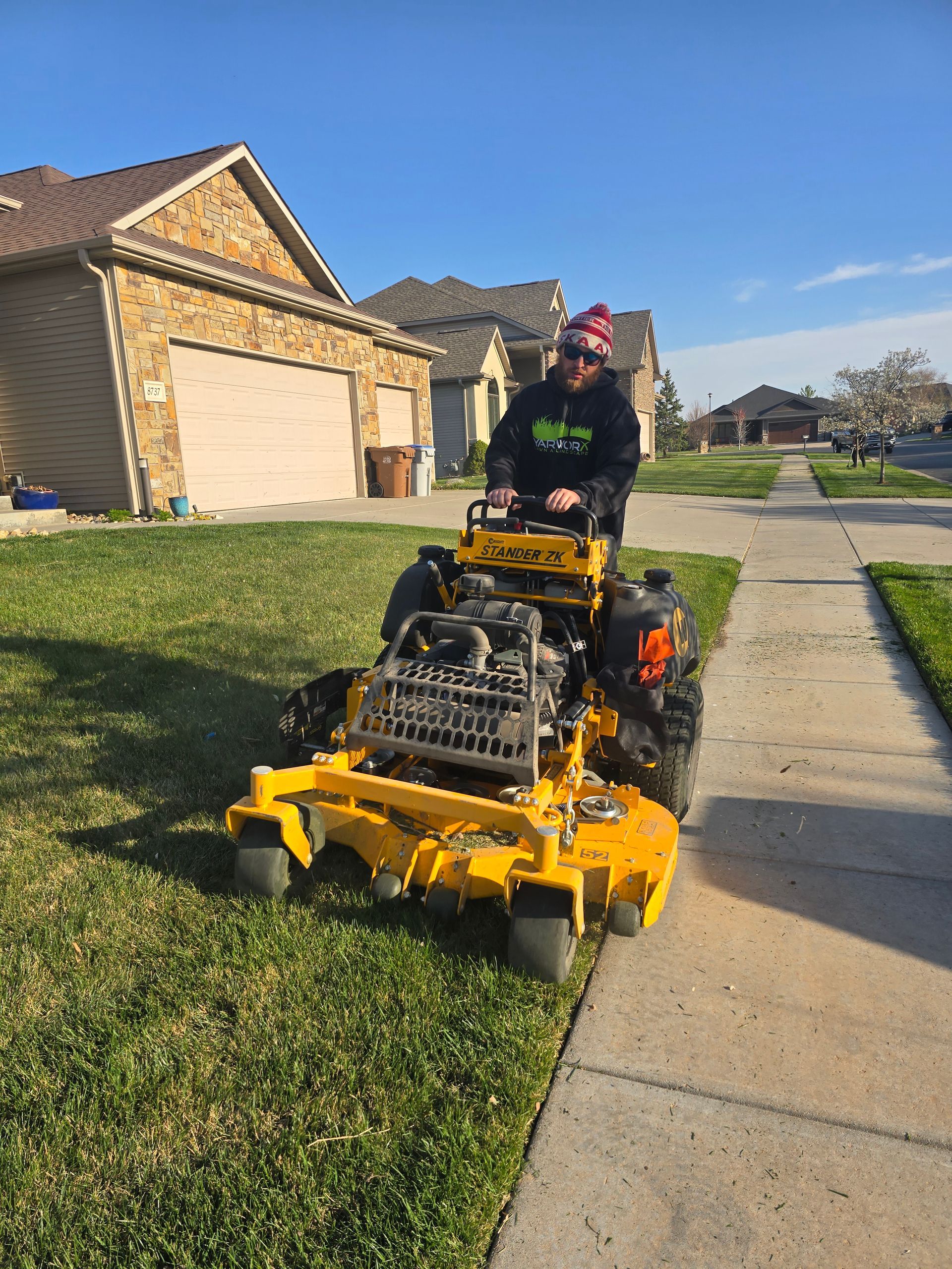 A man is riding a yellow lawn mower on a lush green lawn.