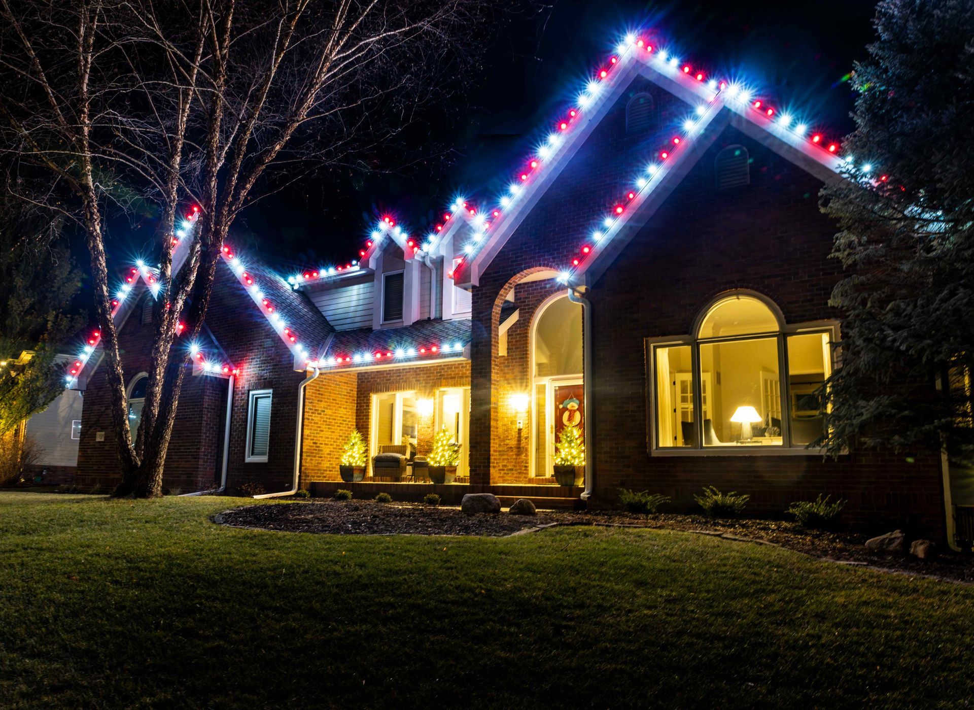 House at night decorated with red, white, and blue Christmas lights.