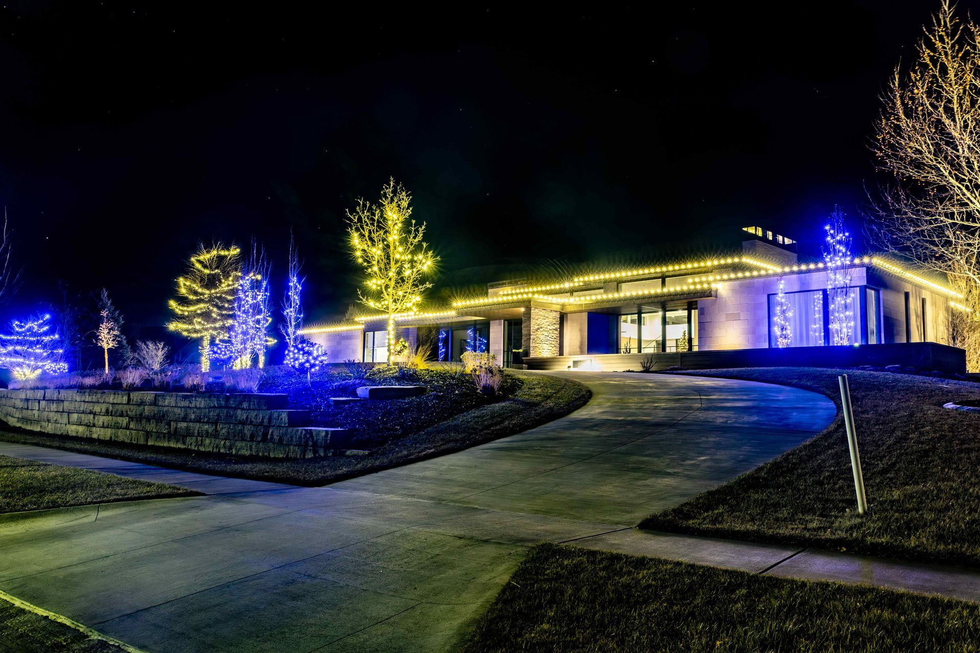 Nighttime view of a house decorated with blue and yellow Christmas lights.