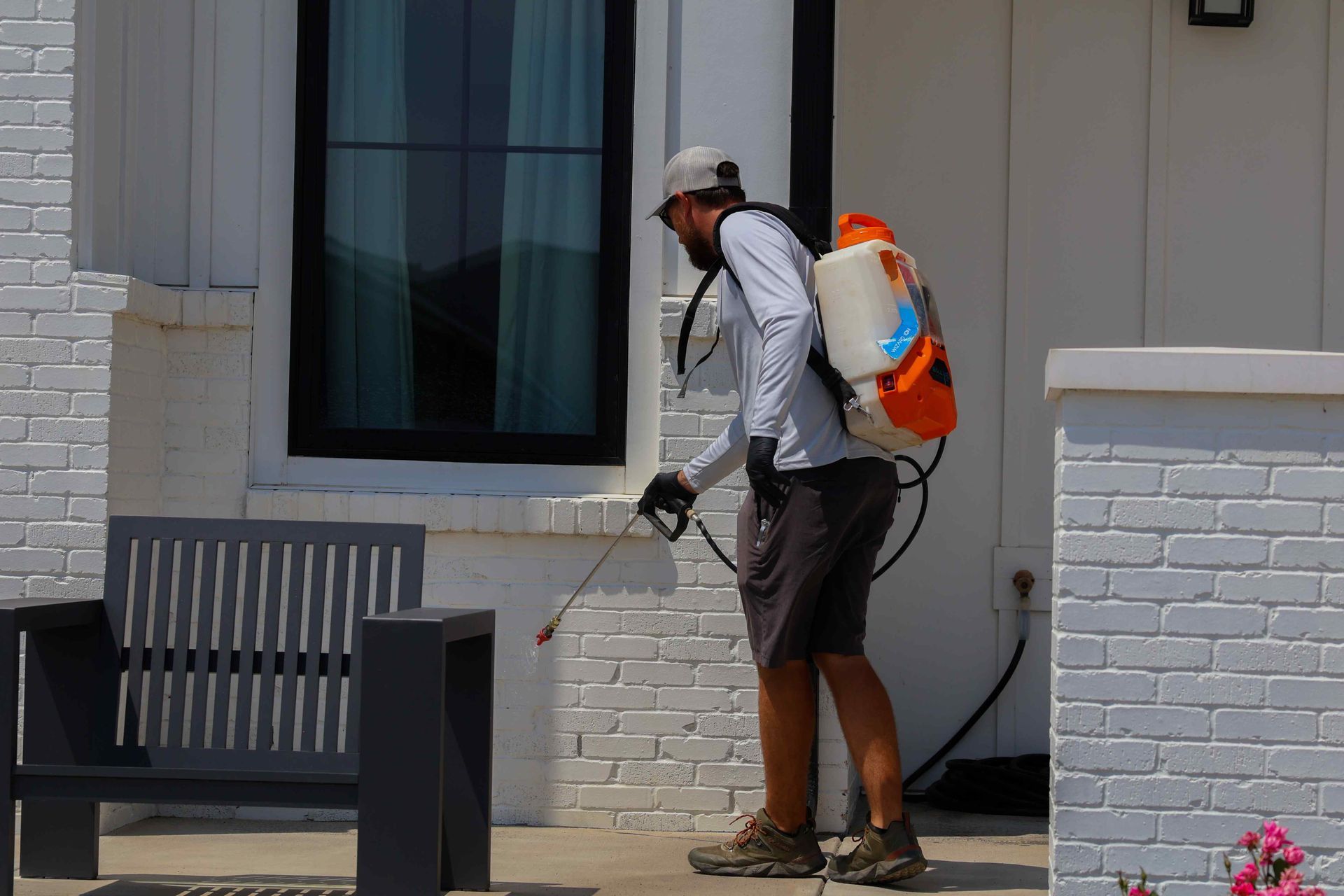 A man is spraying a house with a backpack.