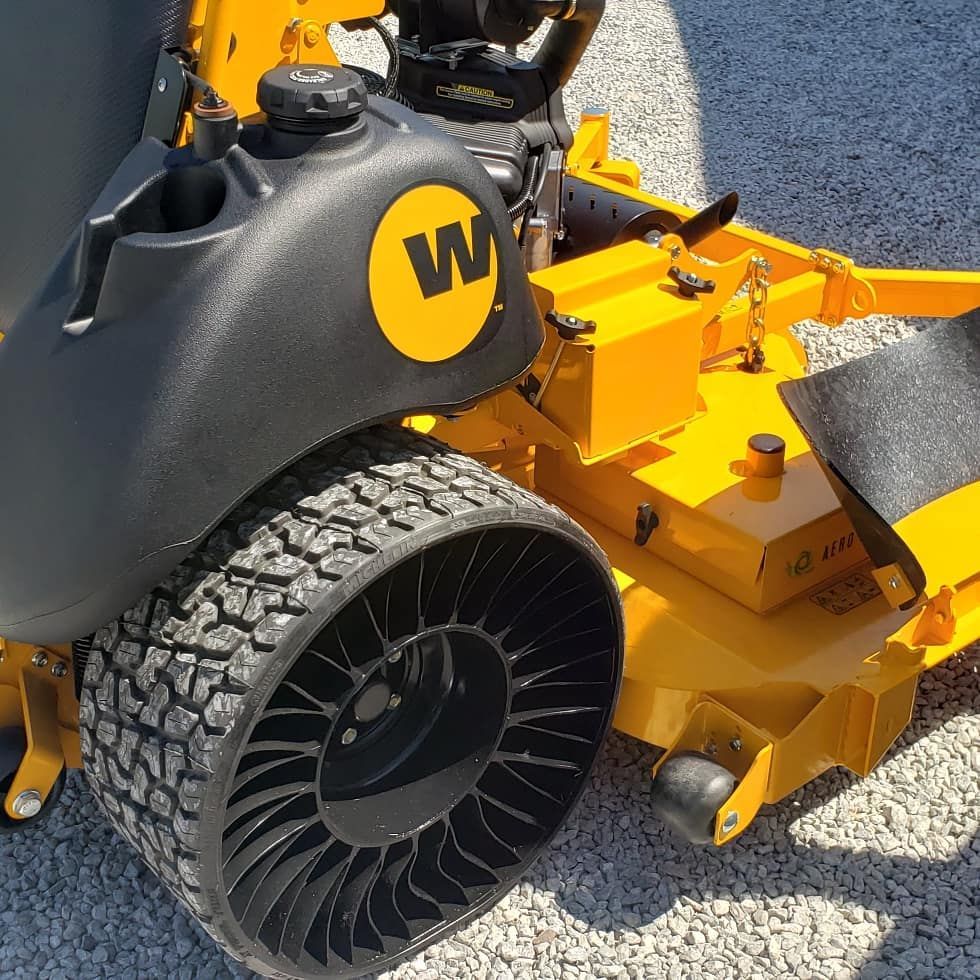 A yellow lawn mower with the letter w on the back
