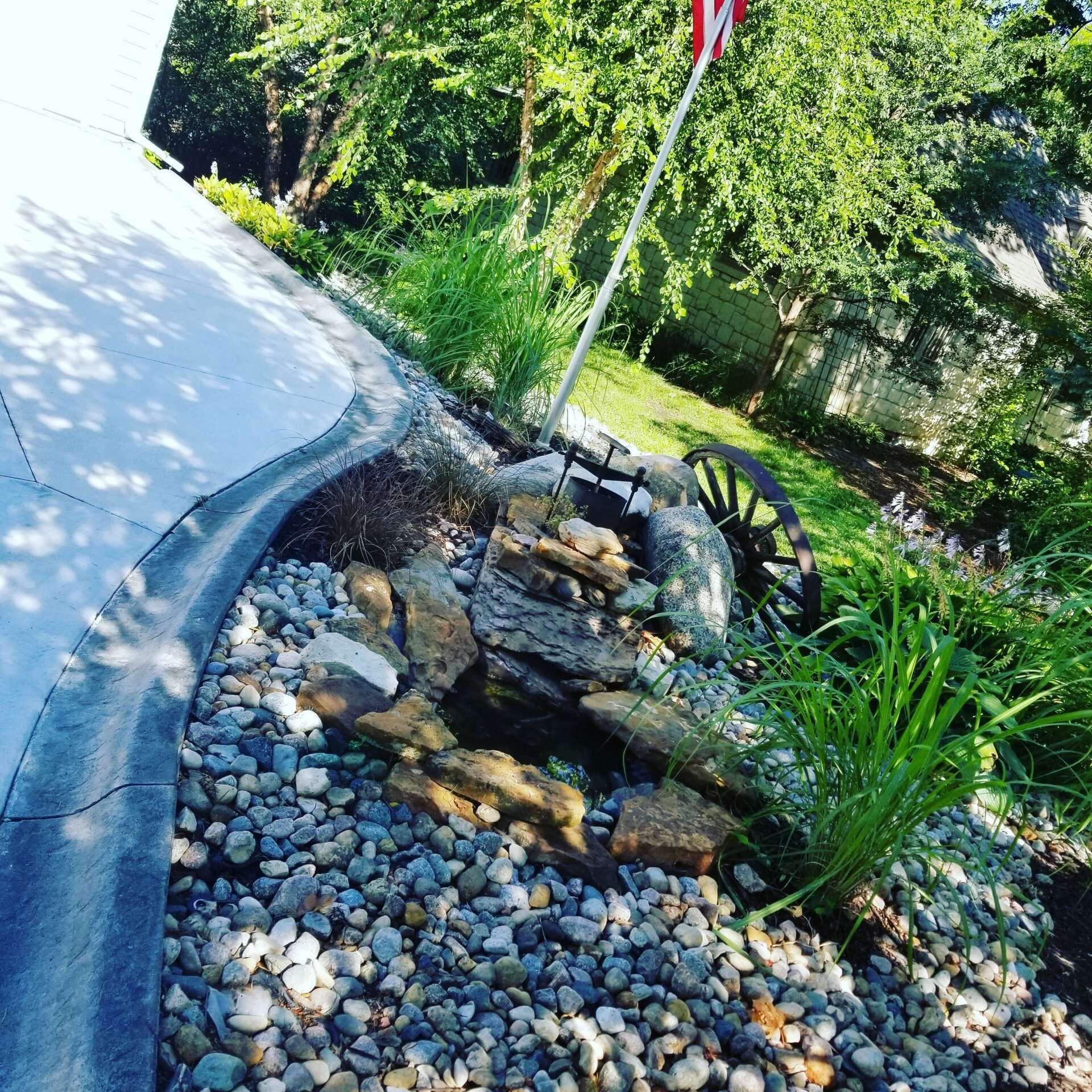 A flag is flying in a garden surrounded by rocks and plants.