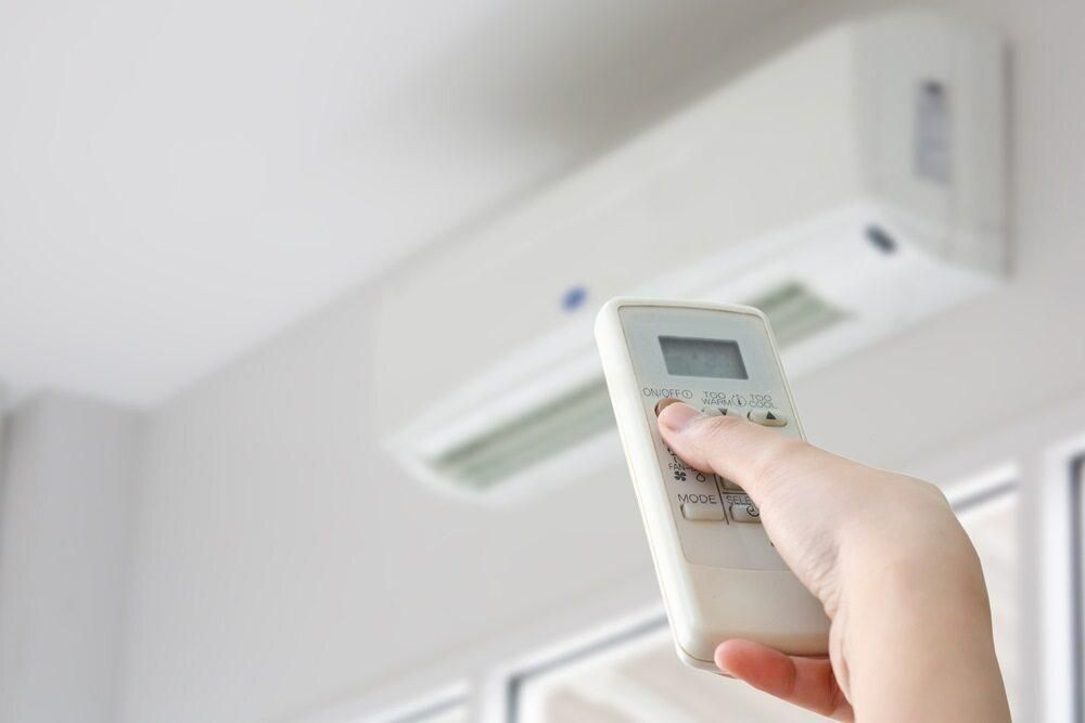 A Person is Holding a Remote Control in Front of an Air Conditioner — AJM's Air Conditioning Centre in Nimbin, NSW