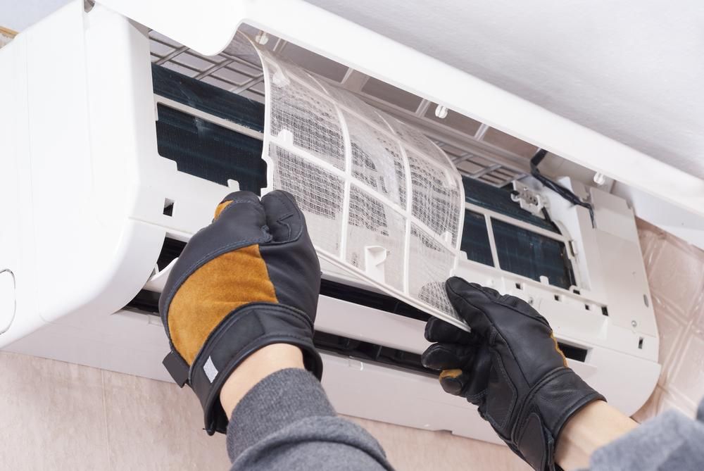 A Person is Cleaning the Filter of an Air Conditioner — AJM's Air Conditioning Centre in Nimbin, NSW