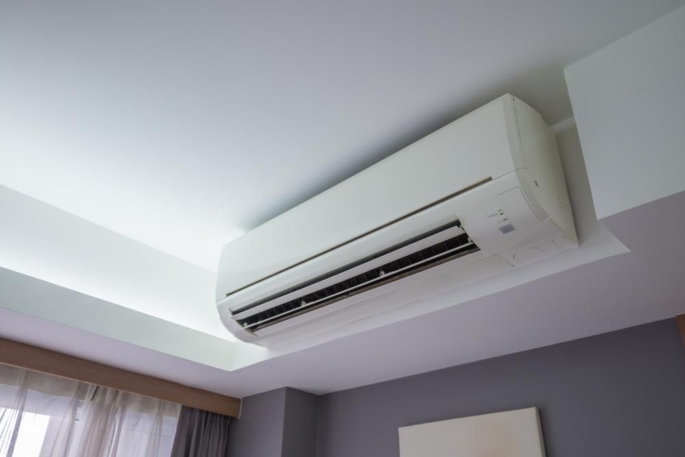 A White Air Conditioner is Hanging From the Ceiling in a Bedroom — AJM's Air Conditioning Centre in Woodburn, NSW