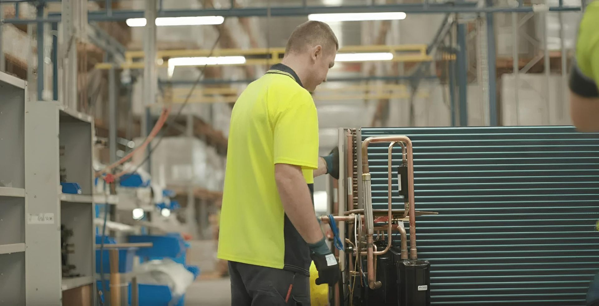 A Man in a Yellow Shirt is Working in a Factory — AJM's Air Conditioning Centre in Lismore, NSW