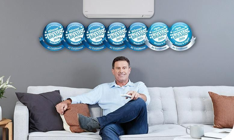 A Man is Sitting on a Couch in a Living Room Under an Air Conditioner — AJM's Air Conditioning Centre in Lismore, NSW