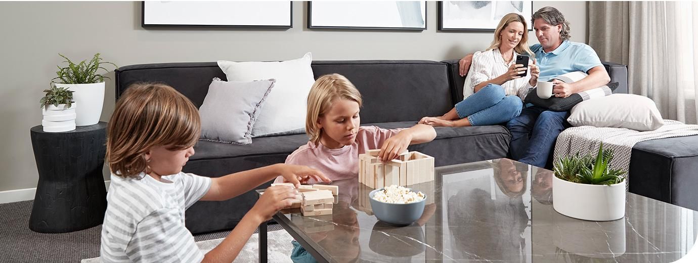 A Family is Sitting on a Couch in a Living Room Eating Popcorn — AJM's Air Conditioning Centre in Lismore, NSW