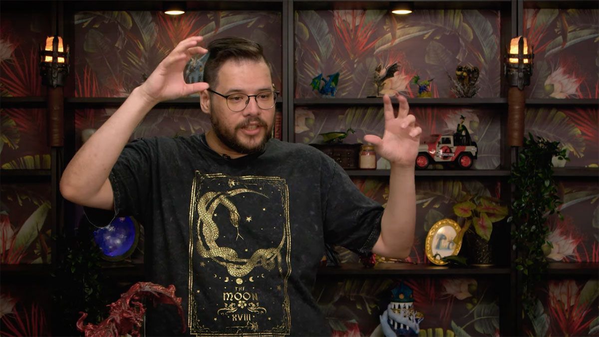 A man wearing glasses and a black shirt is standing in front of a shelf.