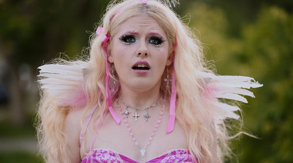 A woman in a pink dress and pink wings is making a funny face.