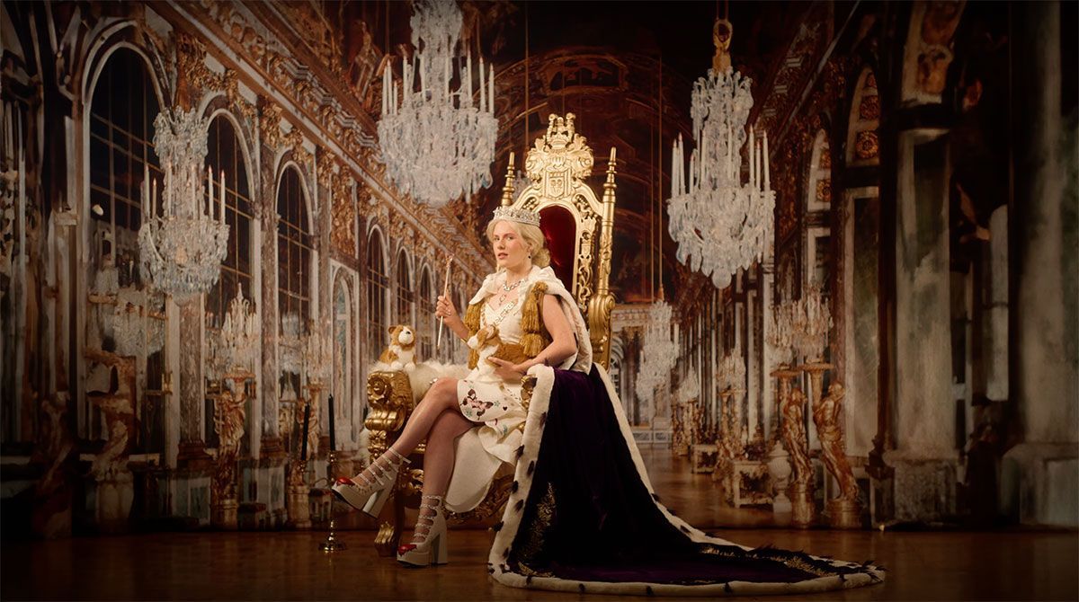 A woman in a costume is sitting on a throne in a room.