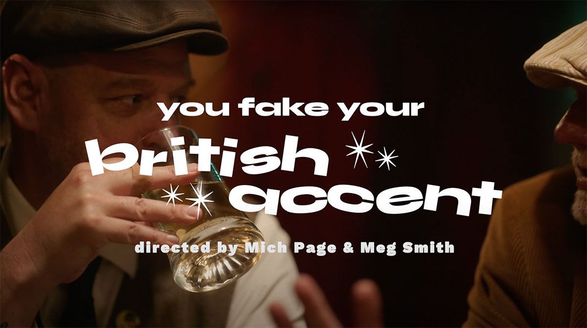 A man in a hat is holding a glass of wine in front of a sign that says you fake your british accent