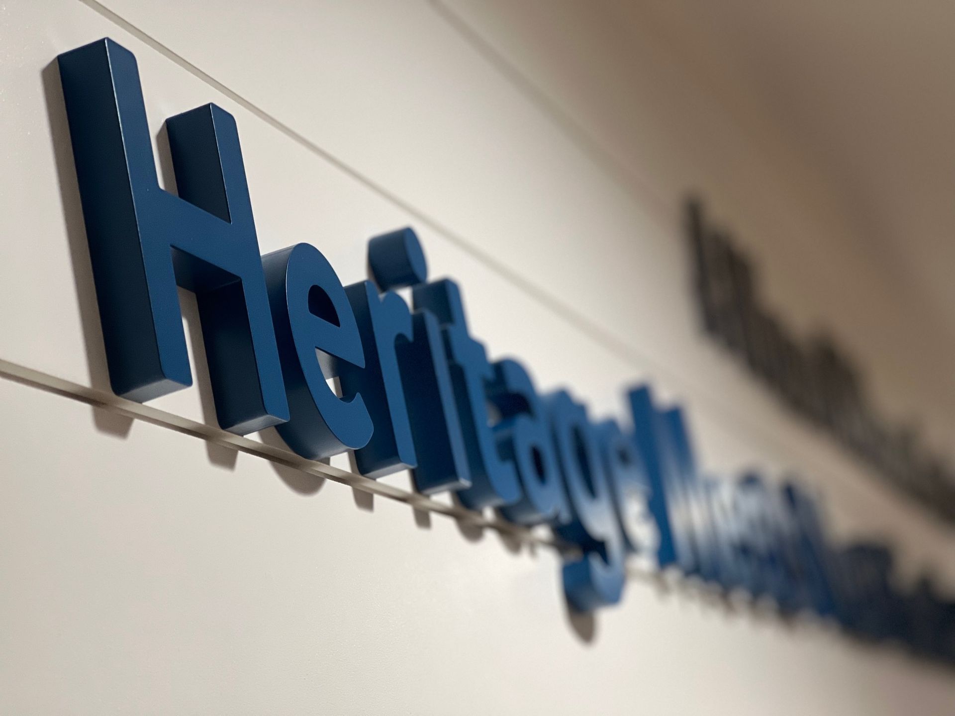 Blue Heffernan sign mounted on a light wall, shot at an angle with shallow depth of field