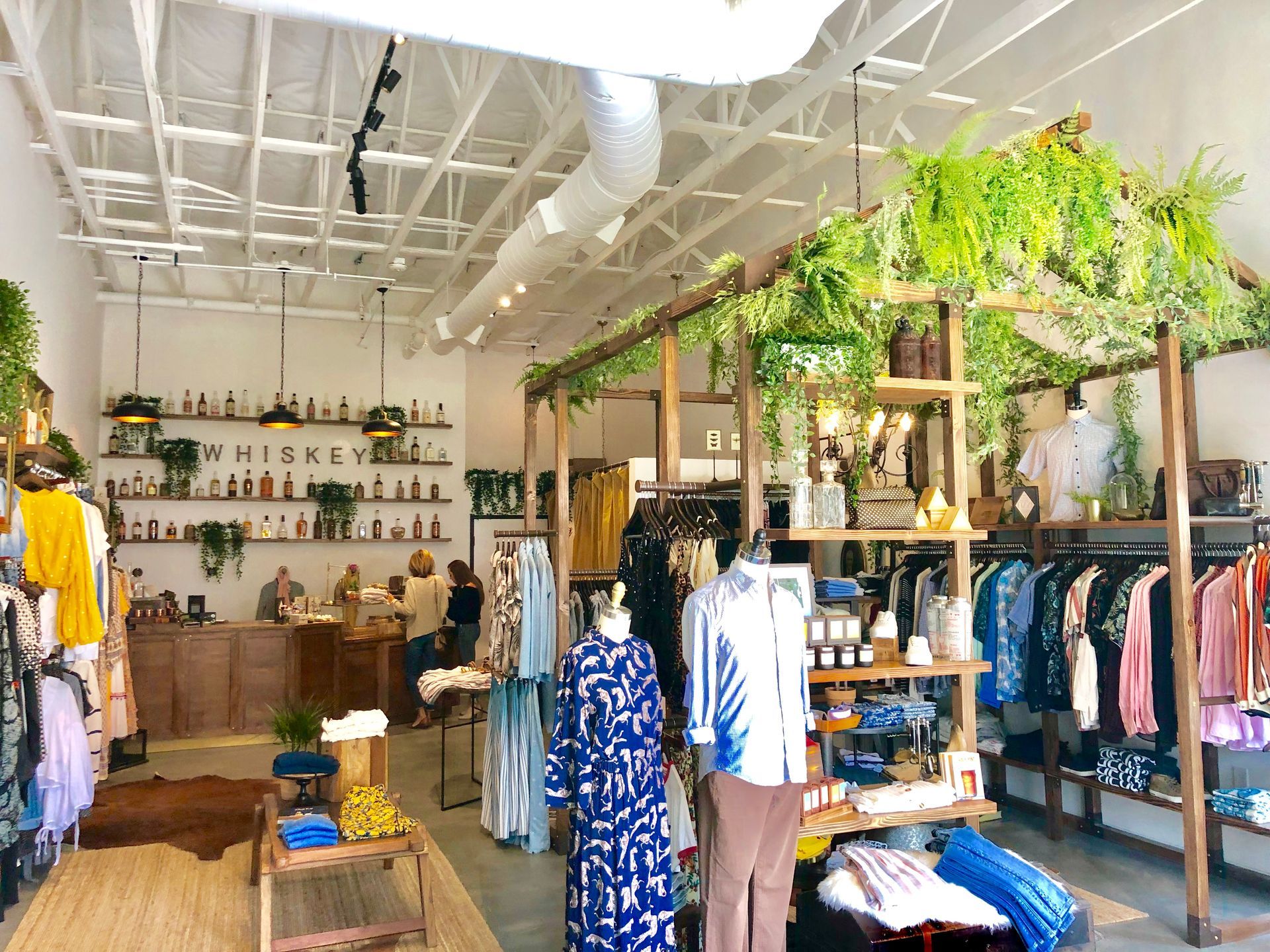 Clothing boutique with racks of dresses and hanging plants in a bright, airy interior