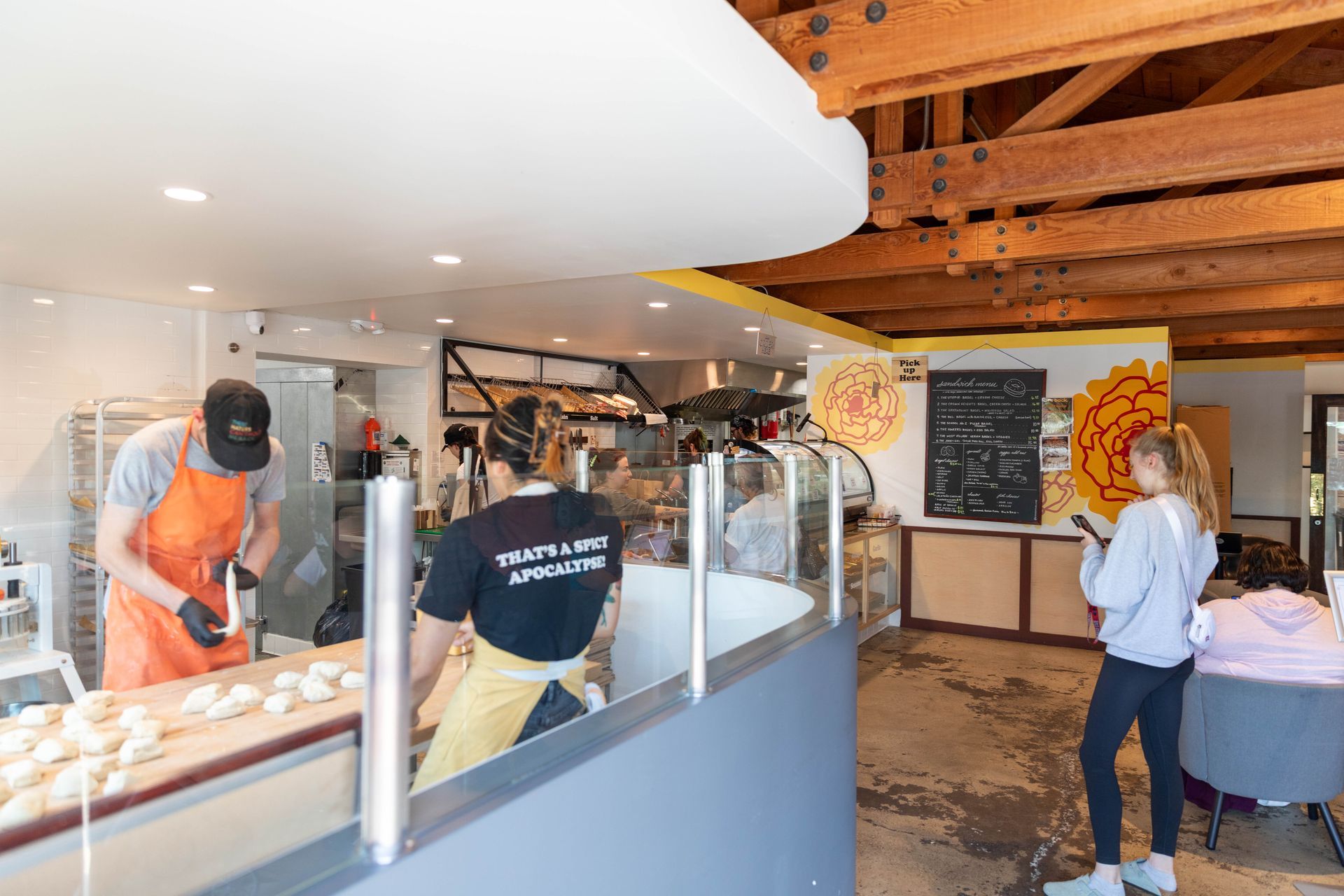 Bakery counter with staff serving pastries and customers inside a bright café