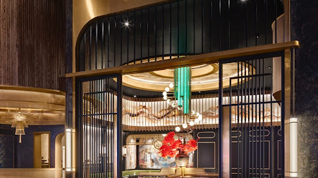 Elegant lobby with black metal lattice, gold accents, hanging chandelier, and red floral arrangement