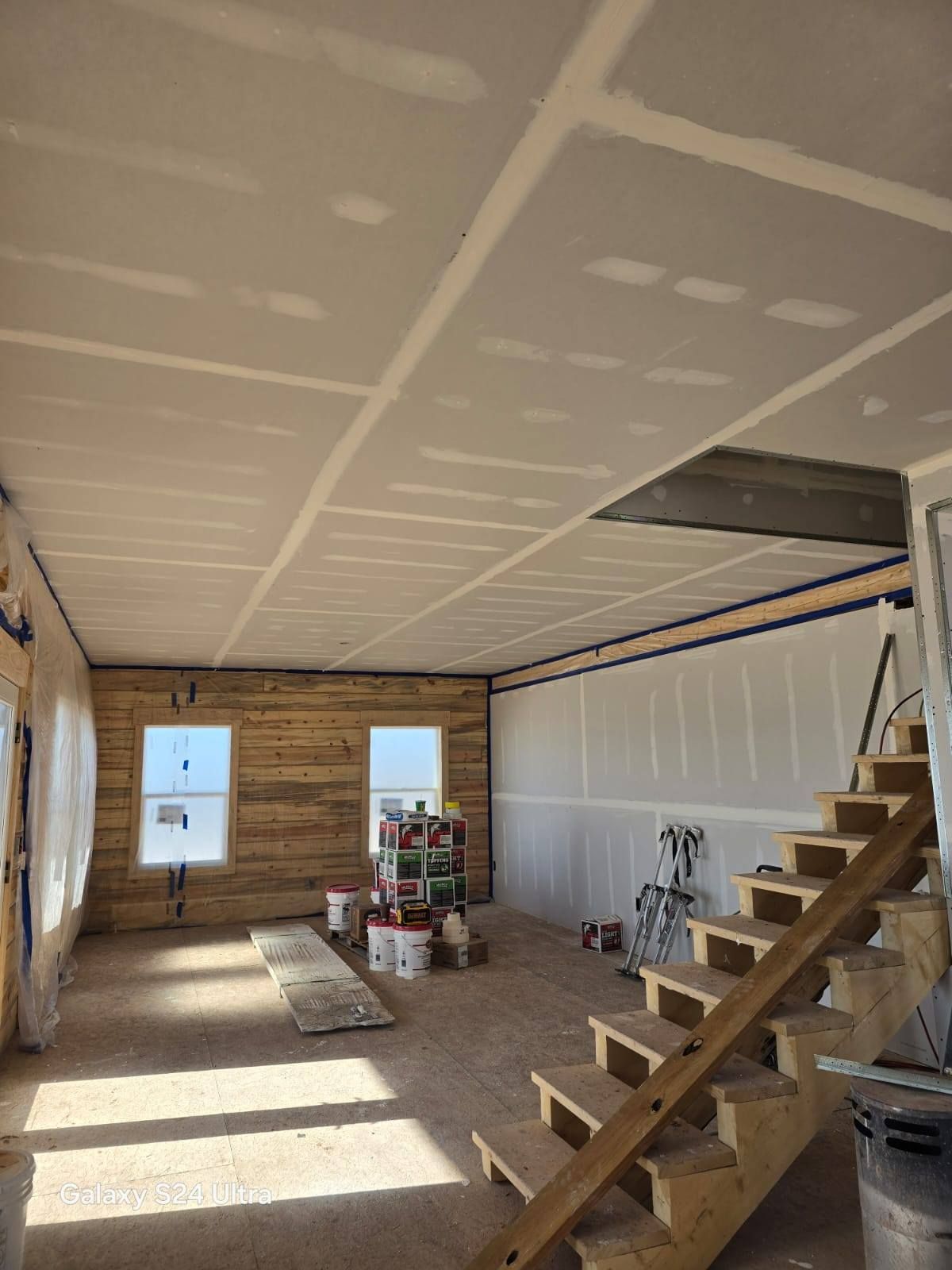 Interior construction: drywall ceiling, wood stairs, unpainted walls.