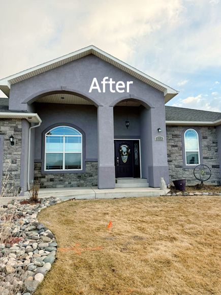 Front of a house with gray stucco and stone, white trim, a black front door, and a brown lawn.