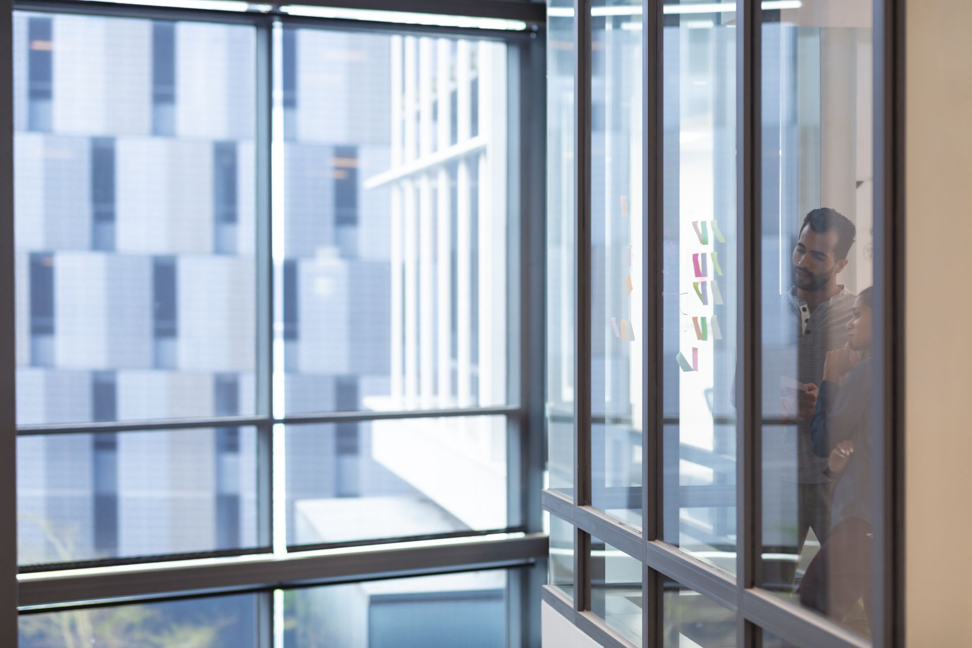 A man is standing in a hallway looking out of a window.