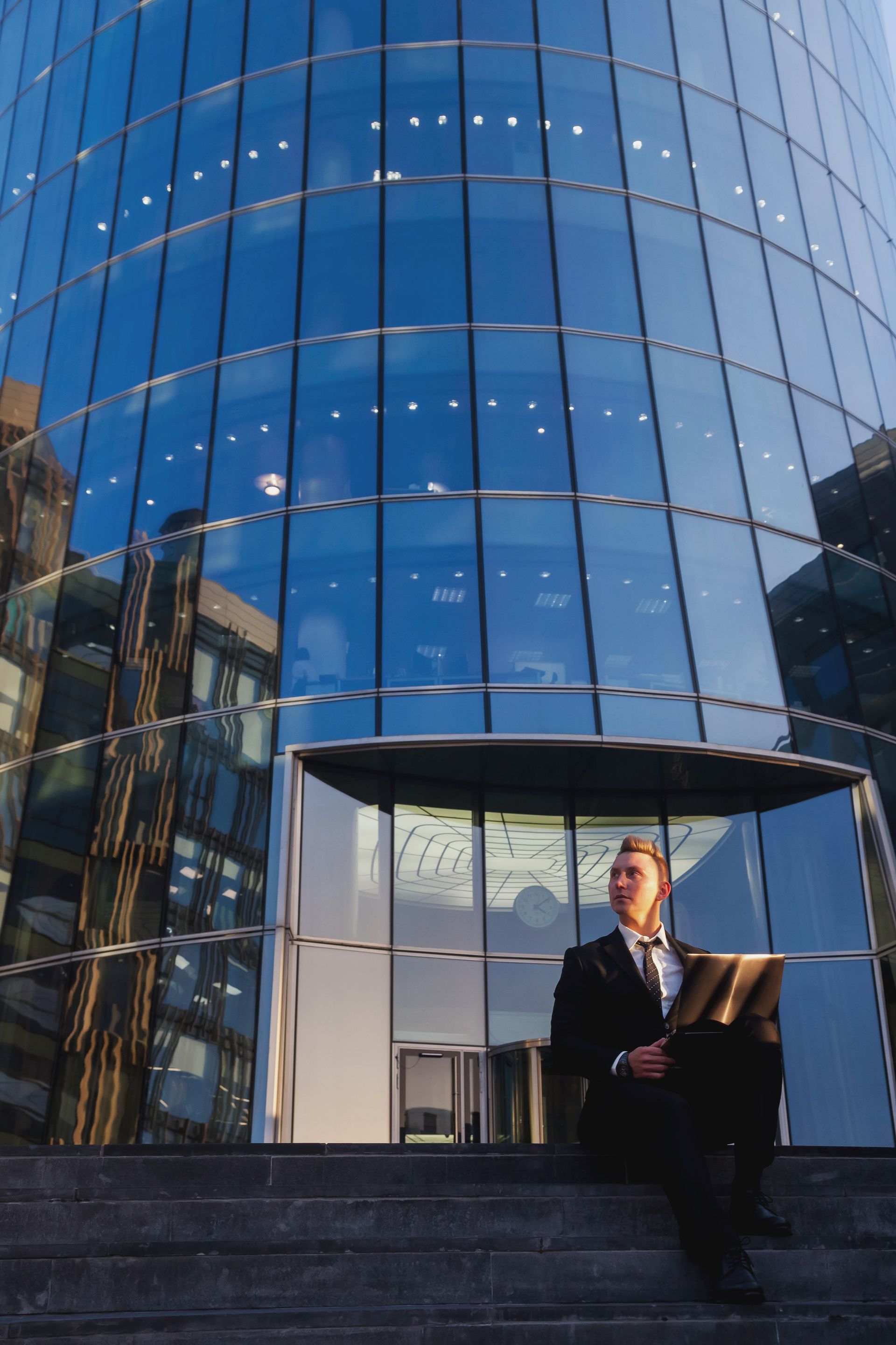 A man is sitting on the steps of a building with a laptop