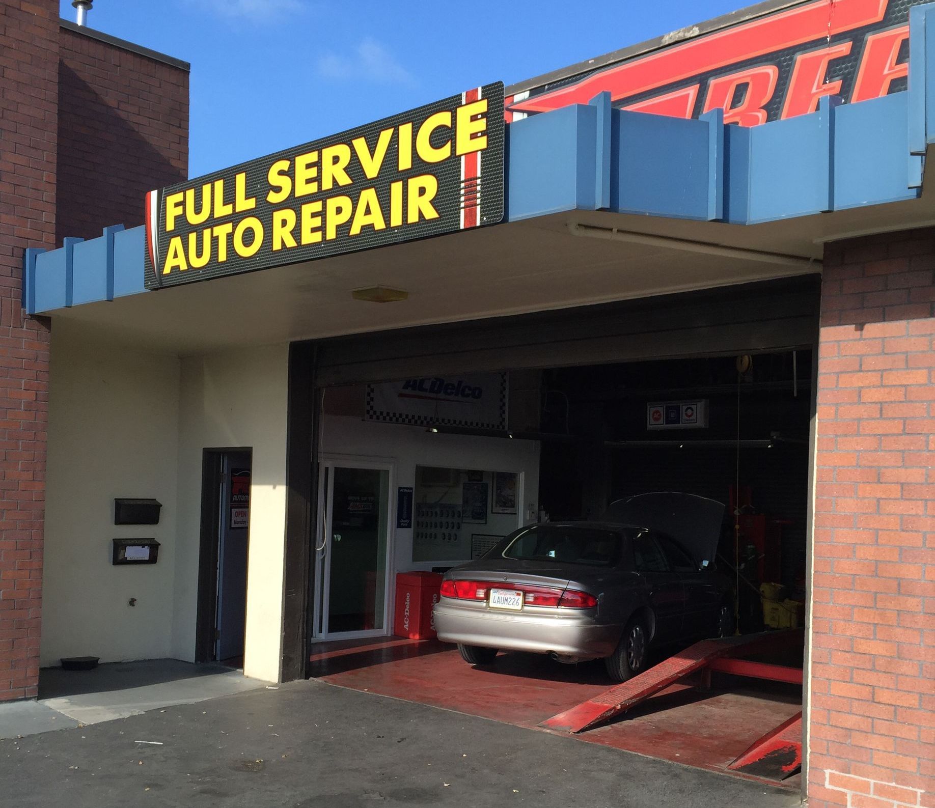 A car is parked in front of a full service auto repair shop