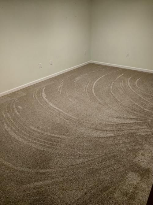 An empty room with a carpeted floor and white walls.