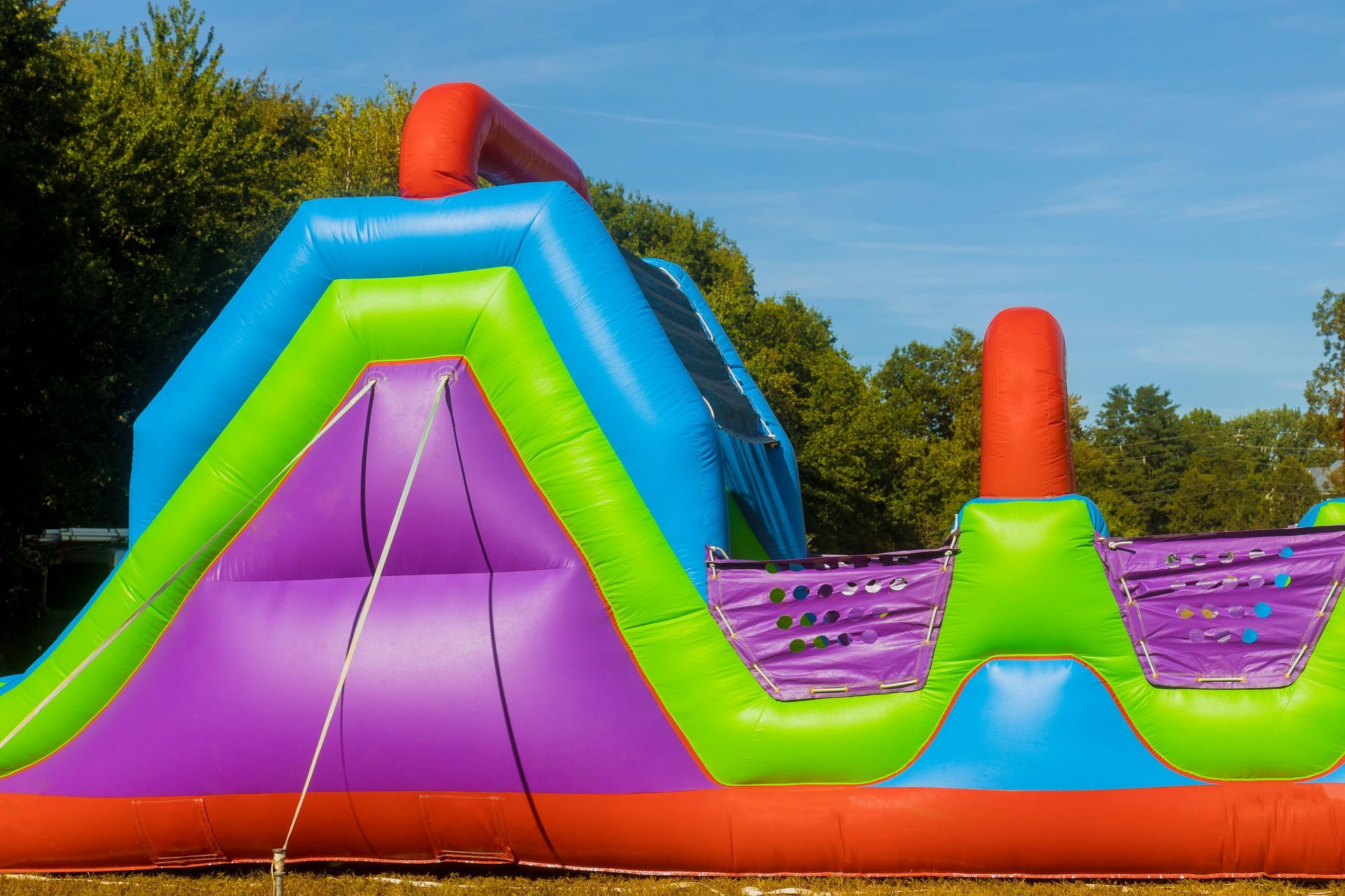 Inflatable colorful obstacle course set outdoors under a blue sky.