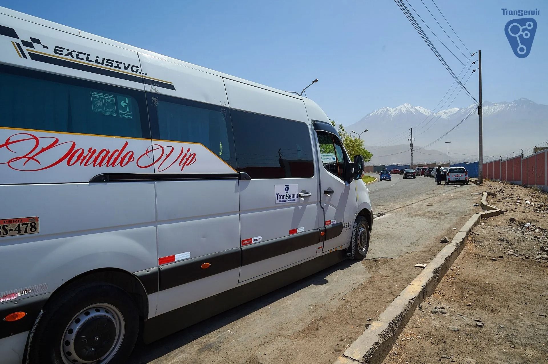 Minibús blanco estacionado al borde de la carretera junto a un arcén de tierra bajo un cielo despejado.