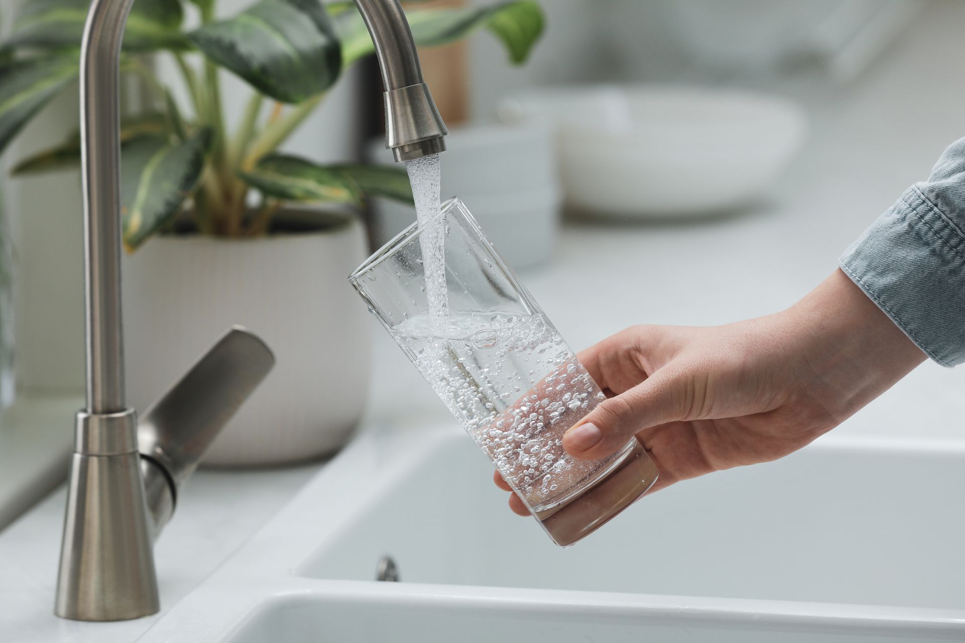 Woman filling glass with water from tap in kitchen, closeup. Woman filling glass with water from tap in kitchen, closeup.