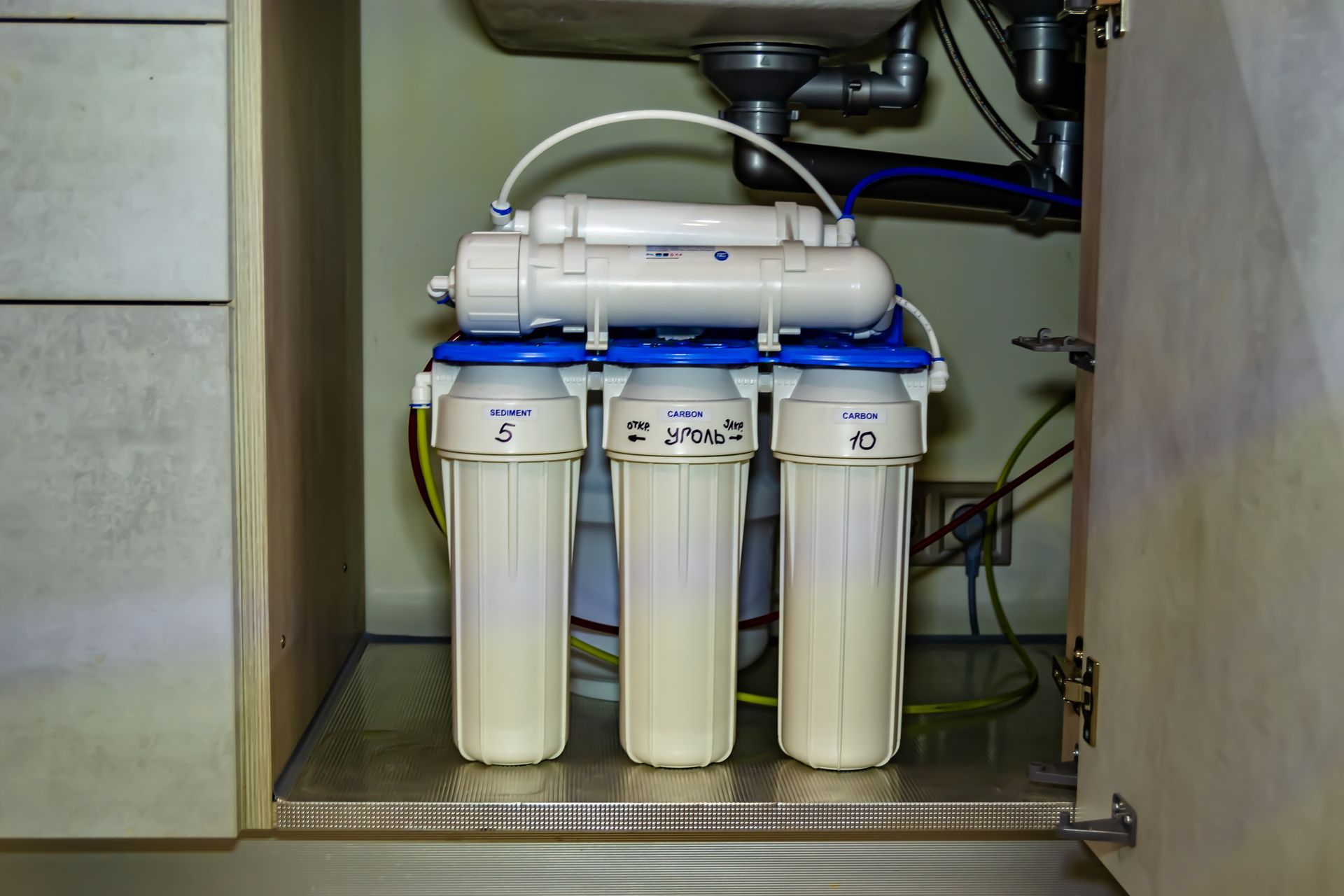 Home water treatment system with modern filters installed in kitchen for clean drinking water.