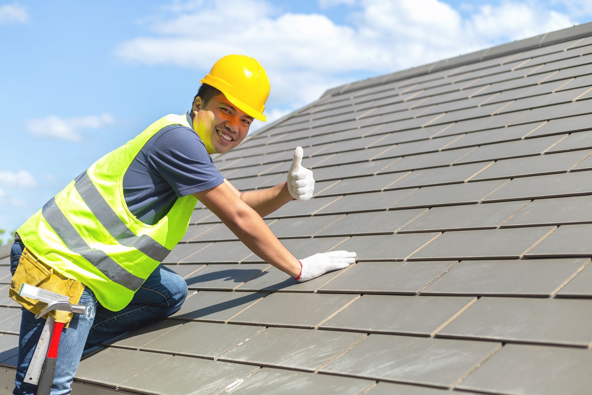 A roofing contractor working on a rooftop, equipped with safety gear, is installing a roof. A builder working on the roof of a new building.