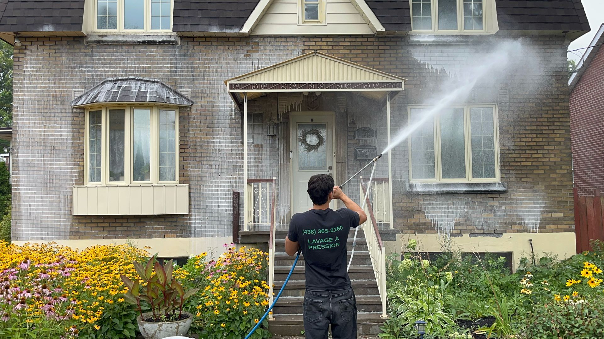 Un homme nettoie la façade d'une maison avec un nettoyeur haute pression.