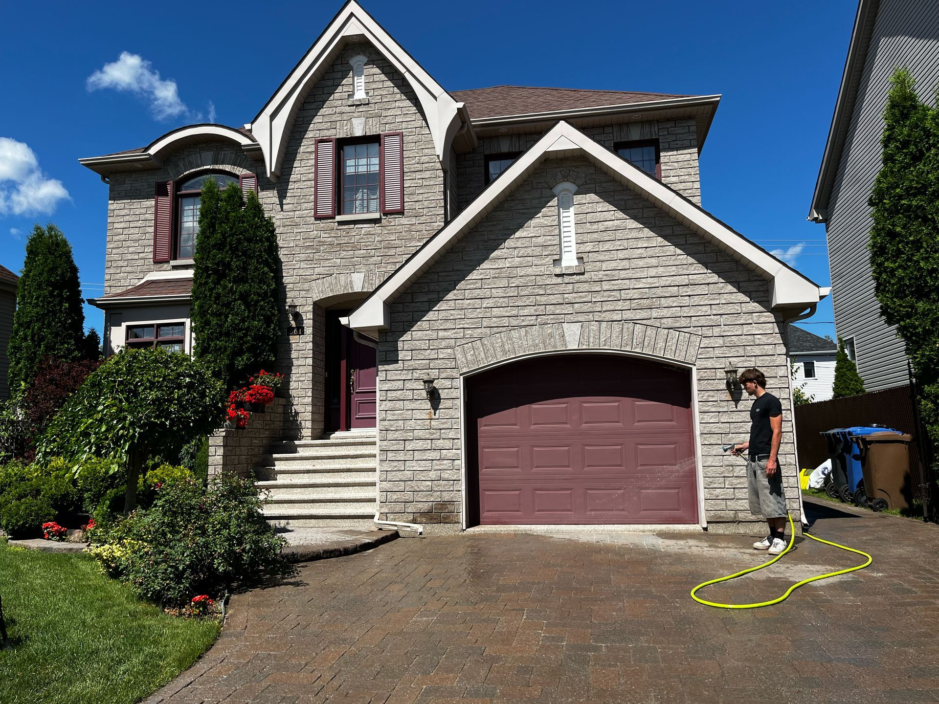Un homme se tient devant une grande maison en briques avec une porte de garage violette