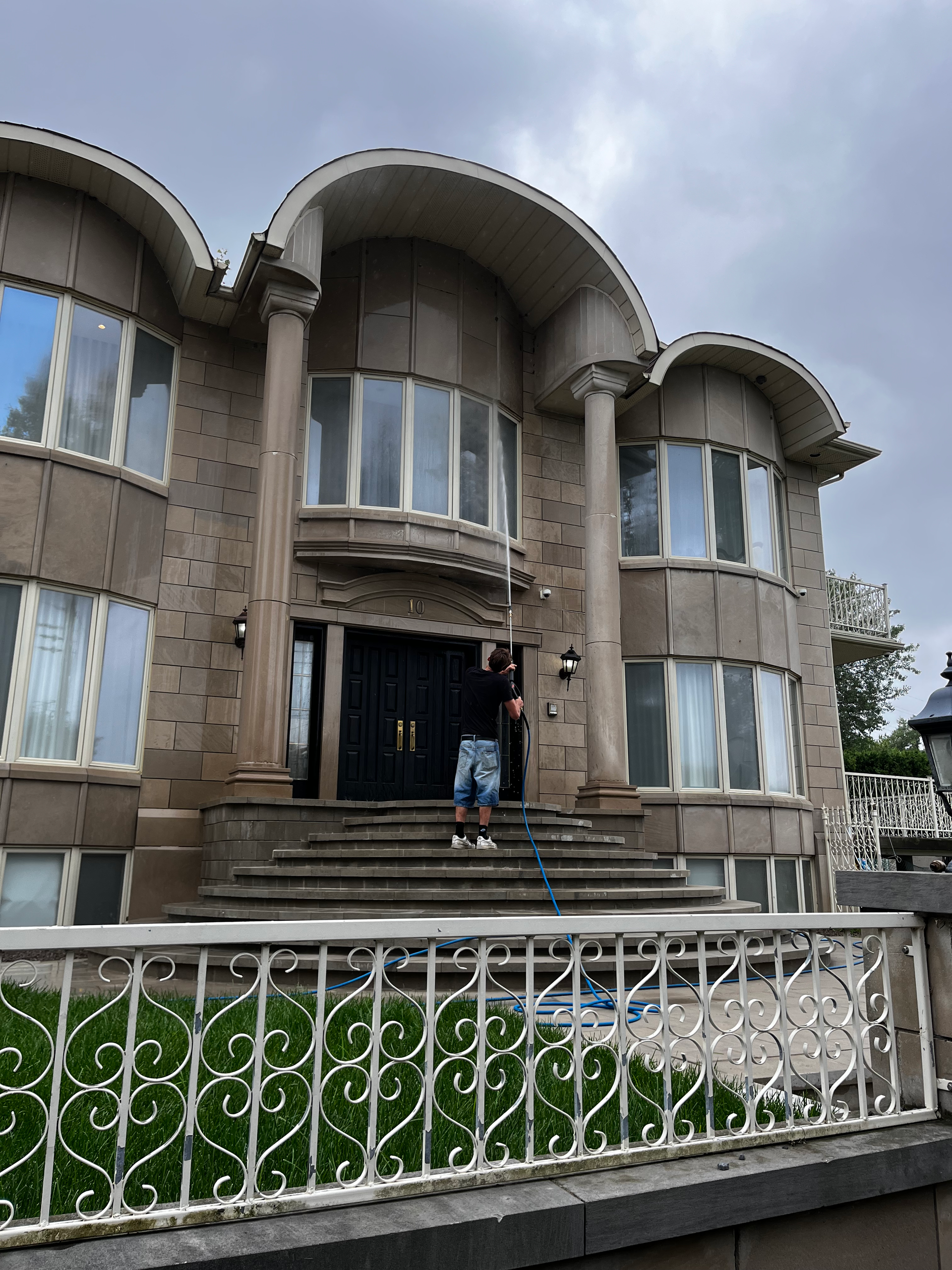 Un homme se tient sur les marches d'une grande maison.